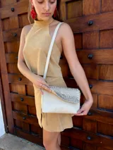 Cartera bandolera de cuero con solapa frontal texturizada en efecto cocodrilo metalizado color dorado. Cuenta con correa larga ajustable y desmontable, cierre principal y forro interno de tela.