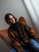 Saco abrigo a cuadros color marrón y negro, con ribete de lino negro, bolsillos frontales y cierre con lazos negros.