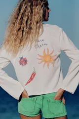 Remera blanca de manga larga y cuello redondo con detalle de texto impreso en el pecho en color azul.