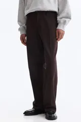 Pantalón sastrero color marrón oscuro, de corte relajado y piernas con pliegues, confeccionado en mezcla de algodón y lyocell. Cuenta con cierre y botón, bolsillos laterales y bolsillos traseros insertados con botón oculto.