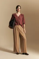 Camisa negra de manga larga con escote en V y cierre frontal de botones. Presenta detalles de volados en los hombros, frunces en la espalda y puños elastizados que le otorgan una silueta relajada y fluida.