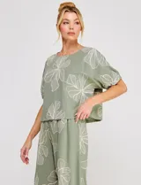 Blusa corta de lino y viscosa color beige, con bordado de grandes flores al tono, cuello redondo, mangas cortas abullonadas y corte holgado.