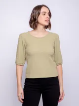 Top de manga tres cuartos color verde oliva, con cuello redondo y tejido texturizado. Las mangas son ligeramente abullonadas.