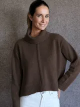 Polerón de lana lambswool color marrón, con cuello alto tipo polera, corte holgado y diseño de costura vertical central. Presenta puños y ruedo acanalados.