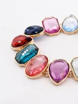 Collar de cadena dorada con dijes de piedras facetadas en colores variados, incluyendo rosa, turquesa, rojo y azul.