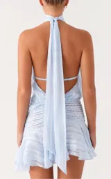 Vestido corto celeste con diseño halter fruncido en el cuello, cuerpo holgado con textura a rayas sutiles, cintura estructurada con fruncidos horizontales y falda con volados.