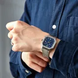 Reloj analógico Casio con caja octagonal de acero inoxidable, esfera azul con textura y malla de eslabones plateada. Cuenta con indicador de fecha y movimiento de cuarzo.