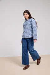 Pantalon de jean azul de corte ancho, con paneles laterales estampados con diseño floral sutil y costuras visibles.