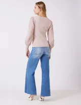 Buzo de tejido lurex marca Nanette, con cuello redondo y mangas largas con diseño plisado. Presenta puños ajustados con aplique de botones decorativos.