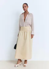Falda midi evasé de tiro medio en color beige, con cintura entallada y bajo deshilachado.