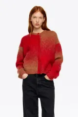 Cardigan corto de corte globo confeccionado en mezcla de alpaca, con botones frontales, escote caja y manga larga con forma. Presenta un diseño bicolor con bloques de color rojo y marrón.
