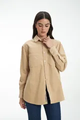 Camisa color arena de pana con cuello clásico, cierre frontal con botones, manga larga con puños abotonados y dos bolsillos de parche en el pecho.