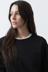 Remera de manga larga en color blanco, con calce relajado y diseño minimalista. Presenta un cuello redondo clásico y puños rectos, ideal para usar como prenda base en capas.