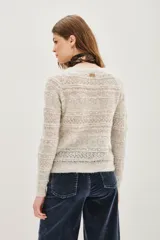 Cardigan de punto calado en color beige, con escote en V y cierre frontal de botones. Presenta un diseño de textura con franjas horizontales y mangas largas.