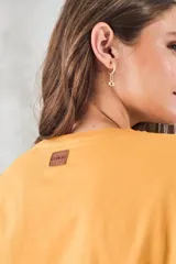 Remera de algodón color mostaza, de manga corta y escote en V con detalle metalizado.