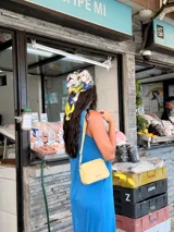 Bandolera pequeña de diseño rectangular en color beige, confeccionada en cuero sintético. Presenta una correa larga ajustable del mismo material y cierre superior con cremallera. Incluye el logo de la marca grabado en la parte frontal.