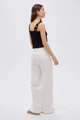 Top de rayón color blanco, de corte ajustado al cuerpo, con escote cuadrado y tirantes anchos decorados con botones metálicos dorados.
