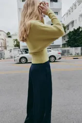 Jersey de punto color verde lima, con cuello pico y manga larga de sisa ancha que se estrecha hacia la muñeca.