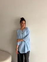 Blusa celeste de manga larga con escote en V y un botón frontal visible.