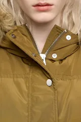 Campera puffer de largo medio en tejido técnico color verde oliva, con cierre frontal de cremallera y botones a presión. Cuenta con capucha con borde de pelo sintético desmontable, bolsillos laterales con cremallera y puños tejidos ajustados.