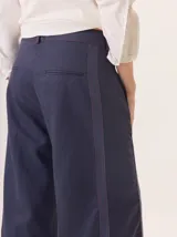 Pantalon de pierna ancha color azul marino, con costuras decorativas en contraste de color rojo y franjas laterales a tono. Cuenta con cintura alta, cierre frontal y bolsillos laterales.