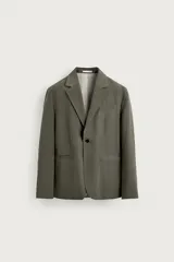 Blazer de corte relaxed fit confeccionada en tejido con mezcla de modal, en color verde militar. Presenta cuello con solapas de muesca, cierre frontal con un botón, bolsillos de vivo en el pecho y bolsillos con solapa en la cadera. Forro interior a rayas y abertura en el centro de la espalda.