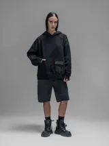 Hoodie oversize color negro, confeccionado en frisa gamuzada de algodón con recortes en hombros y bolsillo frontal tipo cargo con solapa en material técnico. Presenta capucha forrada y puños y ruedo acanalados.