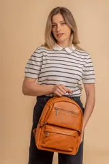 Mochila de cuero sintético color suela, con compartimento principal amplio, bolsillo frontal con cierre y correas ajustables.