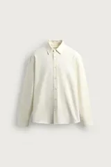 Camisa de corte regular fit confeccionada en mezcla de algodón y seda, color beige, con cuello camisero, manga larga con puños abotonados y cierre frontal de botonadura oculta.