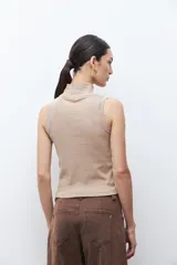 Top sin mangas de tejido canalé en color blanco, con cuello alto tipo tortuga y ajuste al cuerpo.