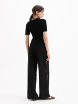 Pantalón sastre color negro de corte recto y tiro alto, confeccionado en mezcla de viscosa y elastano. Presenta bolsillos laterales, presillas para cinto y un delicado vivo decorativo a lo largo de los laterales.