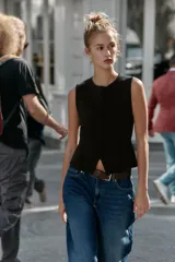 Top negro de punto, sin mangas, con cuello redondo. Presenta costuras marcadas en el frente y un bajo con abertura frontal que simula un peplum ajustado.