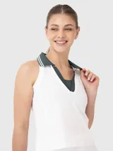 Top deportivo sin mangas con cuello polo en contraste de color verde oscuro y detalles de líneas blancas. Diseño tipo crop con tejido acanalado y tecnología de secado rápido.