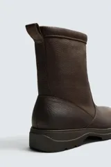 Bota de cuero con acabado abatanado, horma redonda y suela track con volumen. Cuenta con plantilla interior de cuero y tirador en la parte trasera.