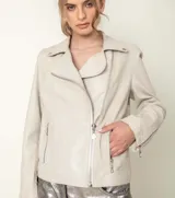 Campera motoquera color blanco hueso de cuero sintético, con cuello solapa, cierre cruzado con cremallera metálica, bolsillos laterales con cierre y mangas largas con cremalleras en los puños.