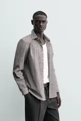 Camisa de corte regular fit confeccionada en algodón, con diseño de rayas verticales finas, cuello italiano, manga larga con puños abotonados y cierre frontal de botones.