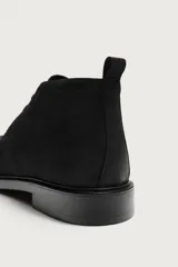 Bota de caña baja con cordones, confeccionada en piel con acabado abatanado de color negro, horma redonda y suela con ligero tacón.