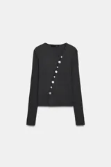 Chaqueta de punto color gris oscuro, con escote en pico y manga larga. Presenta cierre frontal con botones nacarados dispuestos de manera asimétrica.