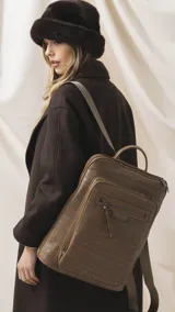 Mochila marrón con textura símil cocodrilo, compartimento principal con cierre, amplio bolsillo frontal con cierre y correas ajustables de tela.