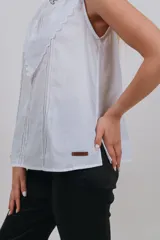 Musculosa blanca sin mangas con detalles de bordado inglés y apliques en el pecho.