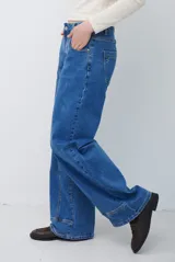 Jean de corte recto y tiro medio, color azul lavado, con costuras verticales decorativas en el frente y ruedo con dobladillo ancho.