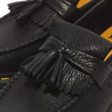 Mocasines Dr. Martens modelo Adrian, confeccionados en cuero negro granulado con detalle de flecos y borlas en el empeine. Presentan las características costuras amarillas en el cerco de la suela y suela gruesa ranurada de goma.