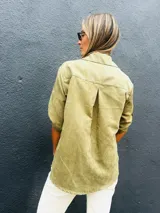 Camisa de gamuza sintética liviana en color verde oliva, con cuello clásico, cierre frontal de botones y mangas cortas con dobladillo.