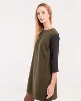 Vestido corto negro con mangas 3/4 verdes, cuello bote y bolsillos laterales.