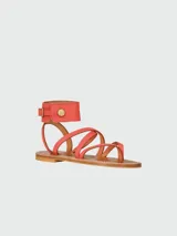 Sandalias planas de cuero color rojo, diseñadas en colaboración entre Longchamp y K. Jacques. Presentan un diseño de tiras finas cruzadas sobre el empeine y una tira ancha envolvente en el tobillo con cierre de hebilla dorada y detalle de botón metálico. La suela es plana de cuero en tono natural.