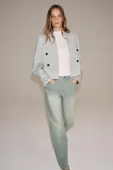 Jeans de tiro bajo y corte recto, confeccionados en denim con estampado de rayas verticales y efecto lavado. Presenta cinco bolsillos, trabillas en la cintura, cierre frontal con cremallera y botón, y un detalle de rotura en la parte delantera.