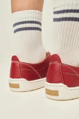 Zapatillas de cuero blanco con diseño minimalista, cordones al tono y suela de goma color suela con costura vista.