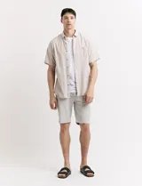 Camisa de manga corta con cuello abotonado y estampado a rayas verticales color beige y blanco.