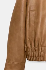 Chaqueta bomber ZW Collection confeccionada en tejido efecto piel de color marrón. Cuenta con cuello subido, manga larga con puño y botón a presión, bolsillos delanteros y bajo recto elástico. Cierre frontal cruzado con botones a presión.