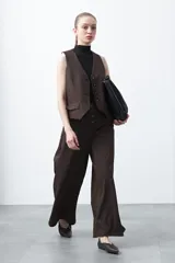 Pantalón wide leg negro de tiro alto con caída fluida y silueta amplia. Presenta cintura alta con botonadura frontal visible.